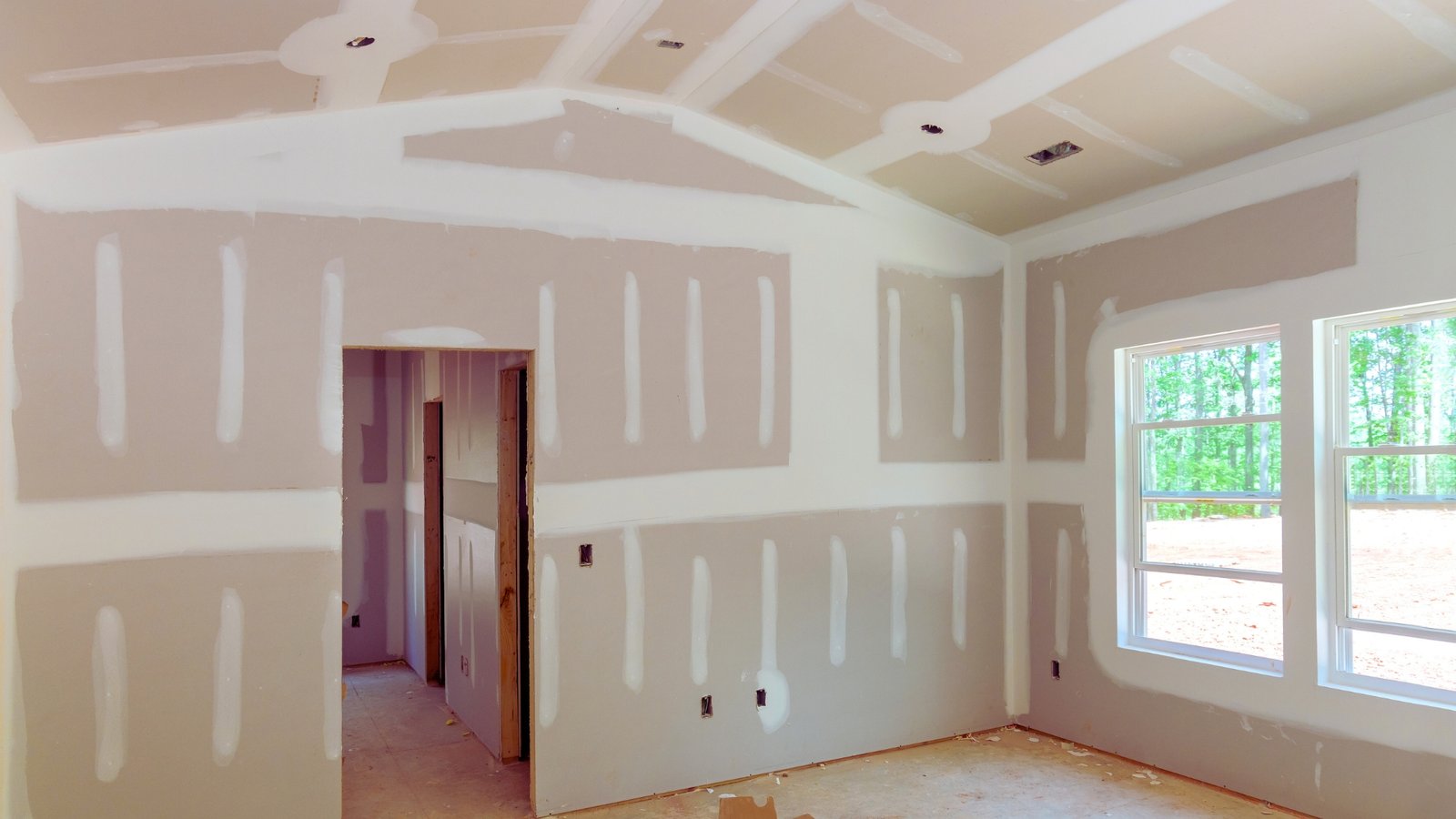 Drywall installation in progress inside a building renovation with unfinished walls and ceiling.