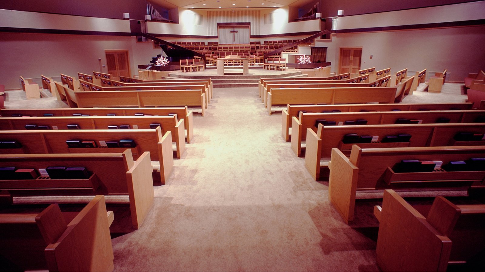 Empty church sanctuary with wooden pews and a stage area at the front.